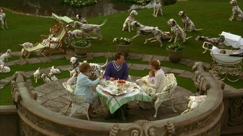 Movie still from “101 Dalmatians” (1996), directed by Stephen Herek – Two women and a child are sitting at a table with food; Wide shot, High angle