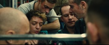 Movie still from “120 BPM” (2017), directed by Robin Campillo – A group of men sitting next to each other on a train; Close Up shot, Over the shoulder angle