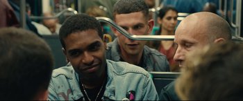 Movie still from “120 BPM” (2017), directed by Robin Campillo – Two men on a subway train one of whom is wearing a jean jacket and the other is wearing a jean jacket; Close Up shot, Over the shoulder angle
