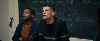 Movie still from “120 BPM” (2017), directed by Robin Campillo – A man sitting in front of a chalkboard; Medium shot, Low angle