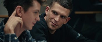 Movie still from “120 BPM” (2017), directed by Robin Campillo – A man sitting next to another man in front of a wall; Close Up shot, Over the shoulder angle