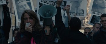 Movie still from “120 BPM” (2017), directed by Robin Campillo – A person holding a megaphone in front of a crowd; Medium shot, High angle
