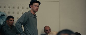Movie still from “120 BPM” (2017), directed by Robin Campillo – A young man wearing a black hat and a gray shirt; Medium shot, Over the shoulder angle