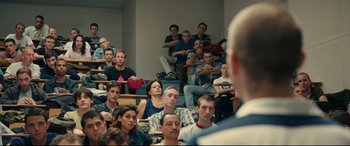 Movie still from “120 BPM” (2017), directed by Robin Campillo – A group of people sitting in front of a man in a lecture hall; Medium shot, High angle