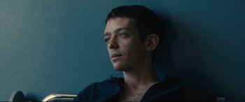 Movie still from “120 BPM” (2017), directed by Robin Campillo – A person sitting in front of a blue wall; Close Up shot, High angle