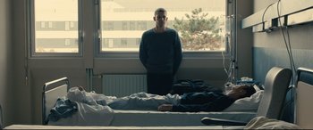 Movie still from “120 BPM” (2017), directed by Robin Campillo – A man standing in front of a bed in front of a window; Wide shot, Low angle