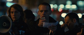 Movie still from “120 BPM” (2017), directed by Robin Campillo – A man is eating a piece of paper while standing in the street; Close Up shot, Over the shoulder angle