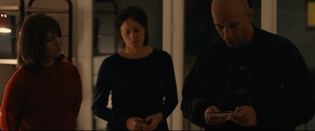 Movie still from “120 BPM” (2017), directed by Robin Campillo – A woman standing next to a man holding a cell phone; Medium shot, Over the shoulder angle