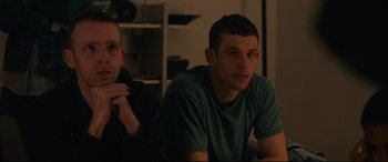 Movie still from “120 BPM” (2017), directed by Robin Campillo – A man sitting next to another man in front of a window; Medium shot, Over the shoulder angle
