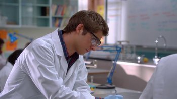 Movie still from “16 Wishes” (2010), directed by Peter DeLuise – A man in a white lab coat is writing in a notebook; Medium shot, Over the shoulder angle