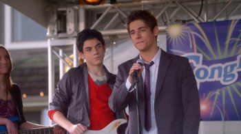 Movie still from “16 Wishes” (2010), directed by Peter DeLuise – Two young men standing next to each other holding microphones; Medium shot, Over the shoulder angle