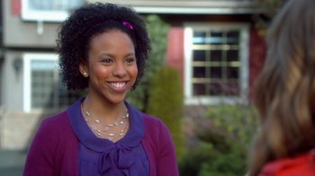 Movie still from “16 Wishes” (2010), directed by Peter DeLuise – A woman smiling for the camera in front of a house; Close Up shot, Over the shoulder angle