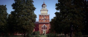 Movie still from “1776” (1972), directed by Peter H. Hunt – A large brick building with a large clock tower; Extreme Wide shot, Low angle