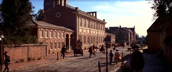 Movie still from “1776” (1972), directed by Peter H. Hunt – A group of people walking down a street near a building; Extreme Wide shot, High angle