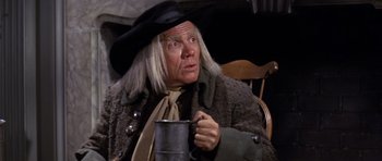 Movie still from “1776” (1972), directed by Peter H. Hunt – An old man in a hat holding a mug; Close Up shot, Over the shoulder angle