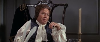 Movie still from “1776” (1972), directed by Peter H. Hunt – A man sitting in a chair holding a pipe; Medium shot, Low angle