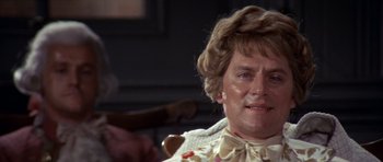 Movie still from “1776” (1972), directed by Peter H. Hunt – An older man with a bow tie is sitting in a chair; Close Up shot, Over the shoulder angle