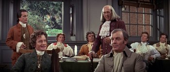 Movie still from “1776” (1972), directed by Peter H. Hunt – A group of people sitting around a table; Medium shot, Over the shoulder angle