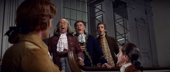 Movie still from “1776” (1972), directed by Peter H. Hunt – A group of men singing in front of a mirror; Medium shot, Low angle