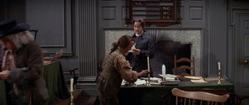 Movie still from “1776” (1972), directed by Peter H. Hunt – A man and a woman standing in front of a table; Medium shot, Over the shoulder angle