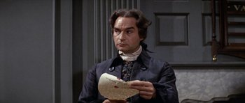 Movie still from “1776” (1972), directed by Peter H. Hunt – A man holding a piece of paper in front of a door; Medium shot, High angle