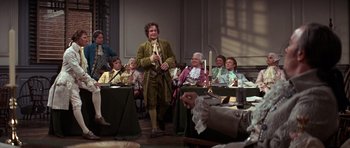 Movie still from “1776” (1972), directed by Peter H. Hunt – A group of people sitting around a room; Wide shot, Over the shoulder angle