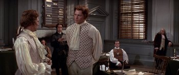 Movie still from “1776” (1972), directed by Peter H. Hunt – A man standing in front of two other men; Medium shot, Over the shoulder angle