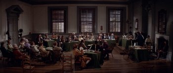 Movie still from “1776” (1972), directed by Peter H. Hunt – A group of people sitting at tables in a room; Extreme Wide shot, High angle