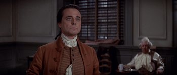 Movie still from “1776” (1972), directed by Peter H. Hunt – A man with long hair wearing a brown jacket and a white shirt; Medium shot, Low angle