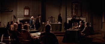 Movie still from “1776” (1972), directed by Peter H. Hunt – A group of people sitting at tables in a dark room; Wide shot, High angle