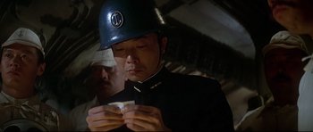 Movie still from “1941” (1979), directed by Steven Spielberg – A man wearing a helmet looking down at a piece of paper; Close Up shot, Low angle