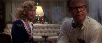 Movie still from “1941” (1979), directed by Steven Spielberg – A man and a woman sitting at a table in front of a couch; Medium shot, Over the shoulder angle