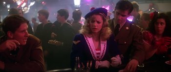 Movie still from “1941” (1979), directed by Steven Spielberg – A woman sitting at a table in a crowded room; Medium shot, Over the shoulder angle