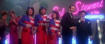 Movie still from “1941” (1979), directed by Steven Spielberg – A group of people dressed in red , white , and blue are singing; Medium shot, Low angle