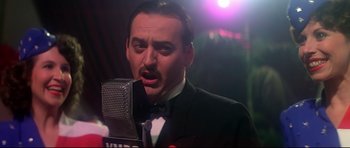 Movie still from “1941” (1979), directed by Steven Spielberg – A man in a suit is singing into a microphone; Close Up shot, Low angle