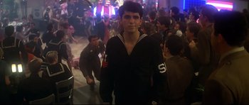 Movie still from “1941” (1979), directed by Steven Spielberg – A young man in a sailor's uniform walks through a crowd; Medium shot, Over the shoulder angle