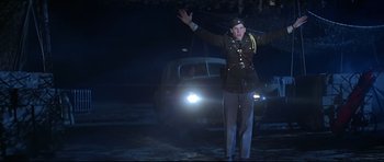 Movie still from “1941” (1979), directed by Steven Spielberg – A man in a military uniform standing in front of a car; Medium shot, Low angle