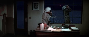 Movie still from “1941” (1979), directed by Steven Spielberg – A man standing at a desk talking on a phone; Medium shot, High angle