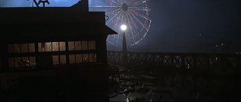 Movie still from “1941” (1979), directed by Steven Spielberg – A ferris wheel with lights in the background at night; Wide shot, Low angle