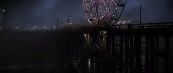 Movie still from “1941” (1979), directed by Steven Spielberg – A ferris wheel is lit up at night on a pier; Extreme Wide shot, High angle