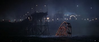 Movie still from “1941” (1979), directed by Steven Spielberg – A night scene of a pier with lights in the background; Extreme Wide shot, High angle