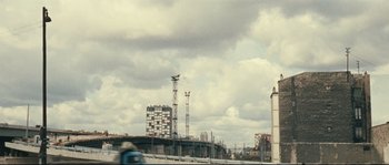 Movie still from “2 or 3 Things I Know About Her” (1967), directed by Jean-Luc Godard – A view of a city skyline with a cloudy sky in the background; Extreme Wide shot, Low angle
