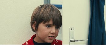 Movie still from “2 or 3 Things I Know About Her” (1967), directed by Jean-Luc Godard – A young boy is looking at the camera while standing in front of a door; Close Up shot, High angle