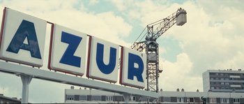 Movie still from “2 or 3 Things I Know About Her” (1967), directed by Jean-Luc Godard – A building with a clock on the top of it; Extreme Wide shot, Low angle