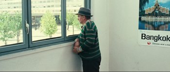 Movie still from “2 or 3 Things I Know About Her” (1967), directed by Jean-Luc Godard – An older man leaning against a wall looking out of a window; Medium shot, Over the shoulder angle