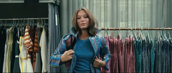 Movie still from “2 or 3 Things I Know About Her” (1967), directed by Jean-Luc Godard – A woman in a blue shirt is holding her jacket; Medium shot, Low angle