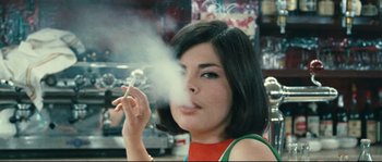 Movie still from “2 or 3 Things I Know About Her” (1967), directed by Jean-Luc Godard – A young woman smoking a cigarette in a store; Close Up shot, Over the shoulder angle