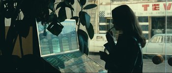 Movie still from “2 or 3 Things I Know About Her” (1967), directed by Jean-Luc Godard – A person is looking at a computer screen in a store window; Medium shot, Over the shoulder angle