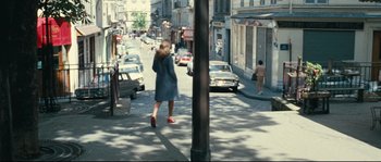 Movie still from “2 or 3 Things I Know About Her” (1967), directed by Jean-Luc Godard – A woman is walking down the street talking on a phone; Wide shot, High angle