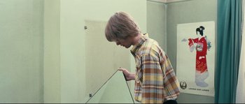 Movie still from “2 or 3 Things I Know About Her” (1967), directed by Jean-Luc Godard – A man looking at his reflection in a mirror; Medium shot, High angle